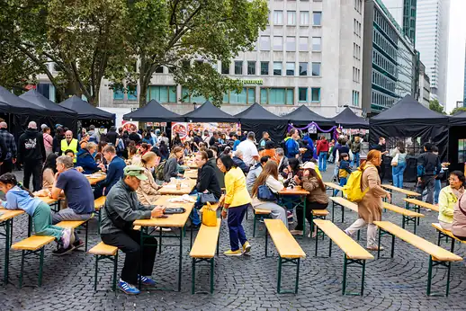 Volle Bänke am Vormittag, Gäste essen zwischen den Zelten