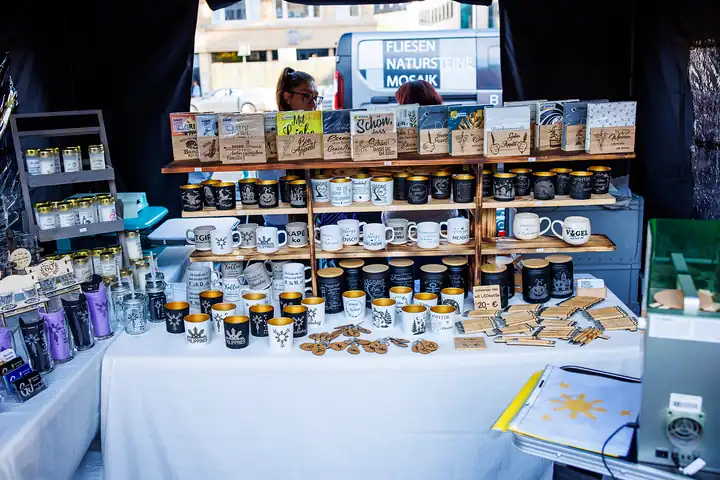Stand mit gravierten Tassen, Holzschildern und Windlichtern