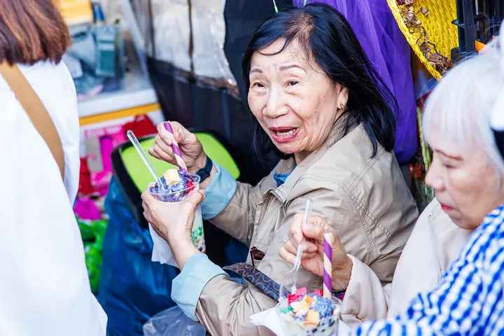 Eine ältere Besucherin mit Halo-Halo dreht sich lachend zur Kamera