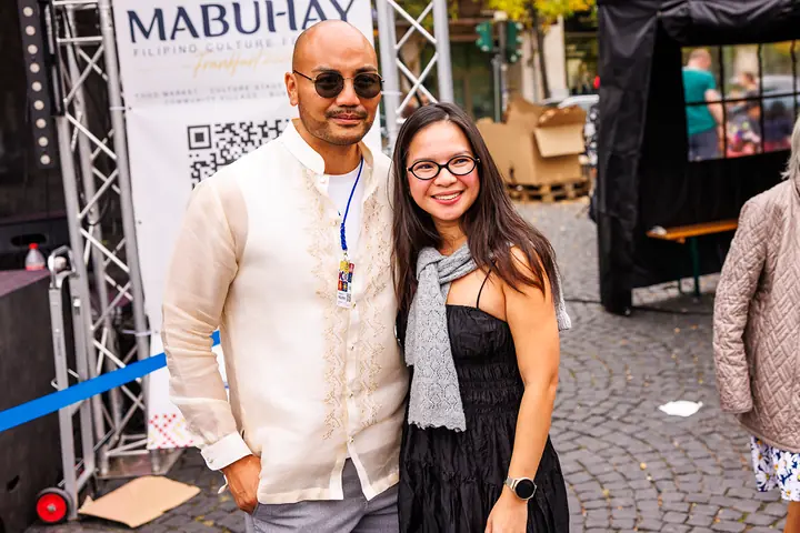 Der Moderator im Barong mit einer Besucherin vor dem MABUHAY-Banner