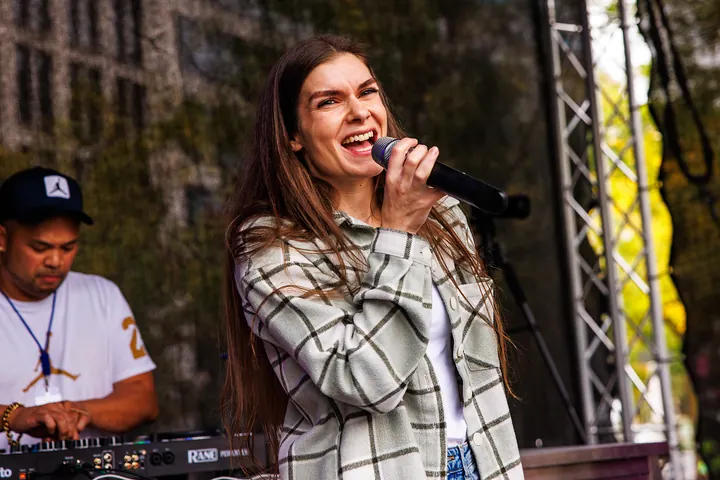 Sängerin im karierten Hemd lacht beim Singen