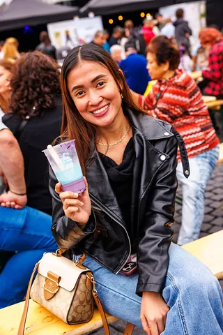 Besucherin auf der Bank mit lila Becherdrink