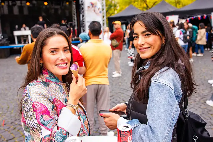 Zwei Frauen lachen, eine hält ein lila Ube-Eis