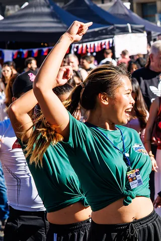 Zwei Tänzerinnen in grünen Shirts reißen die Arme hoch